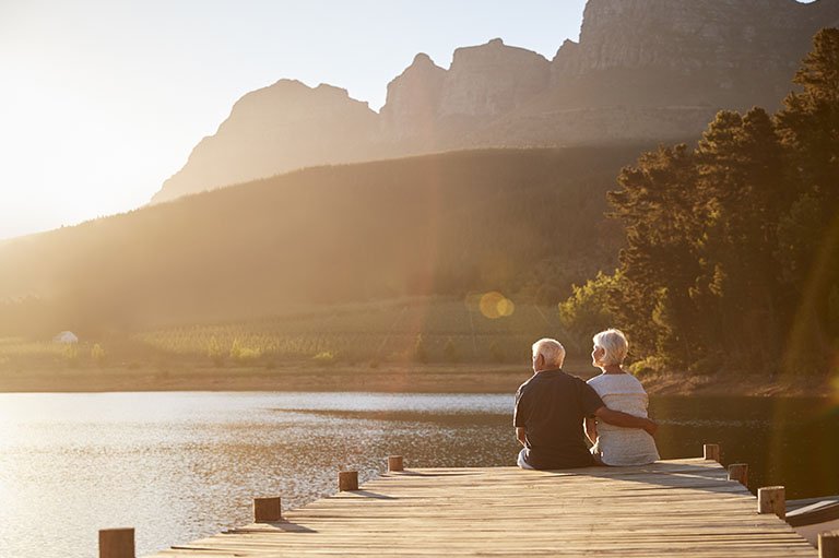 A couple sitting on the lake enjoying retirement.